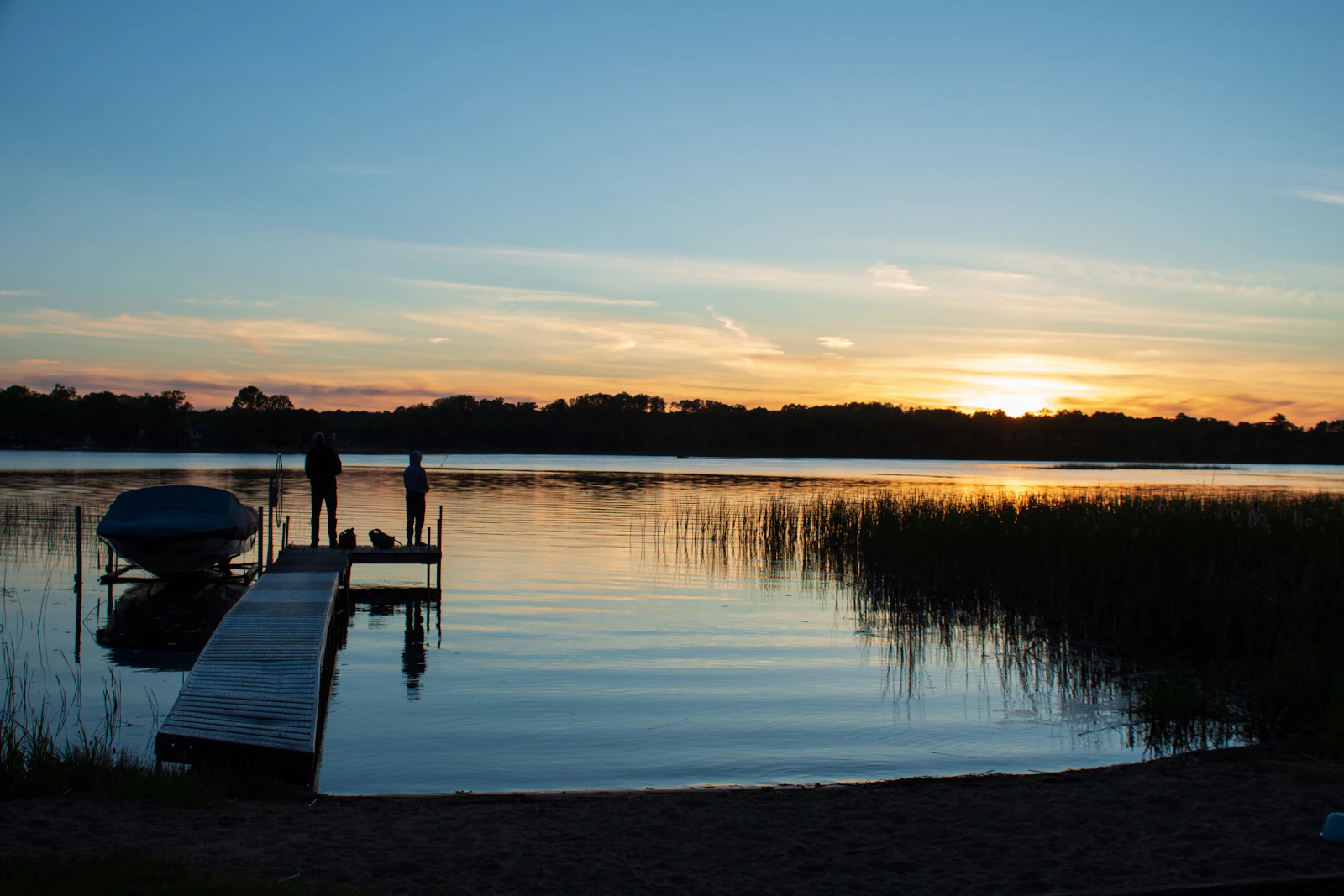 Couple standing on a wooden dock looking out over a lake.