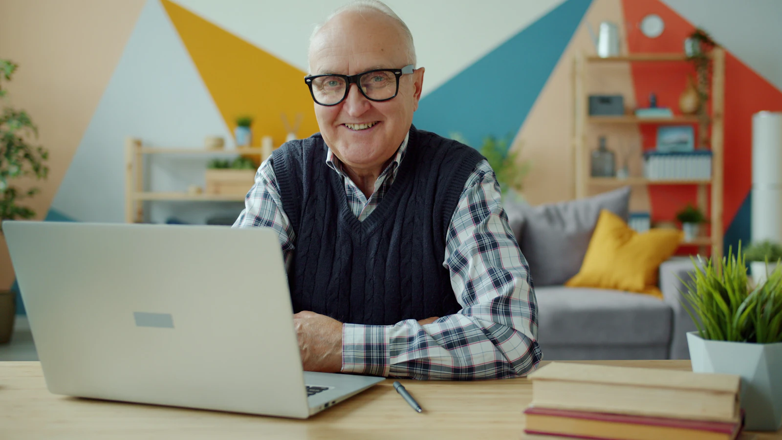 Older man with glasses reading paperwork at a sunlit table.