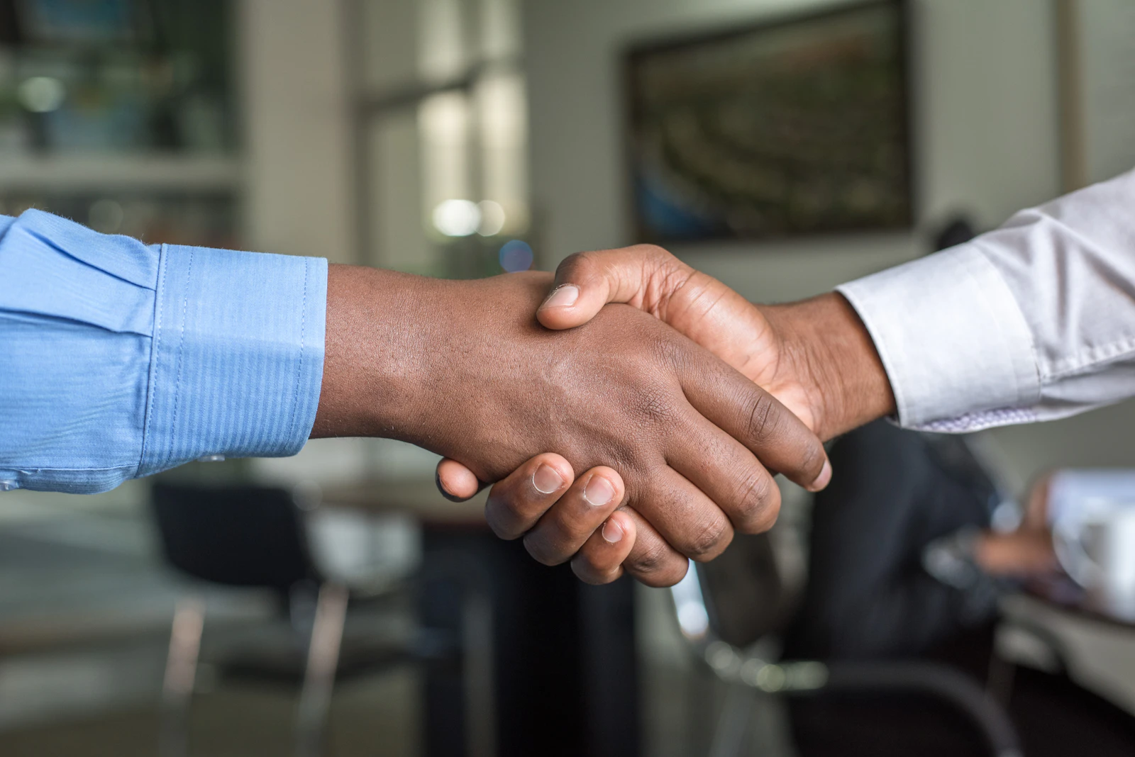 Two people shaking hands over a desk after a planning meeting.